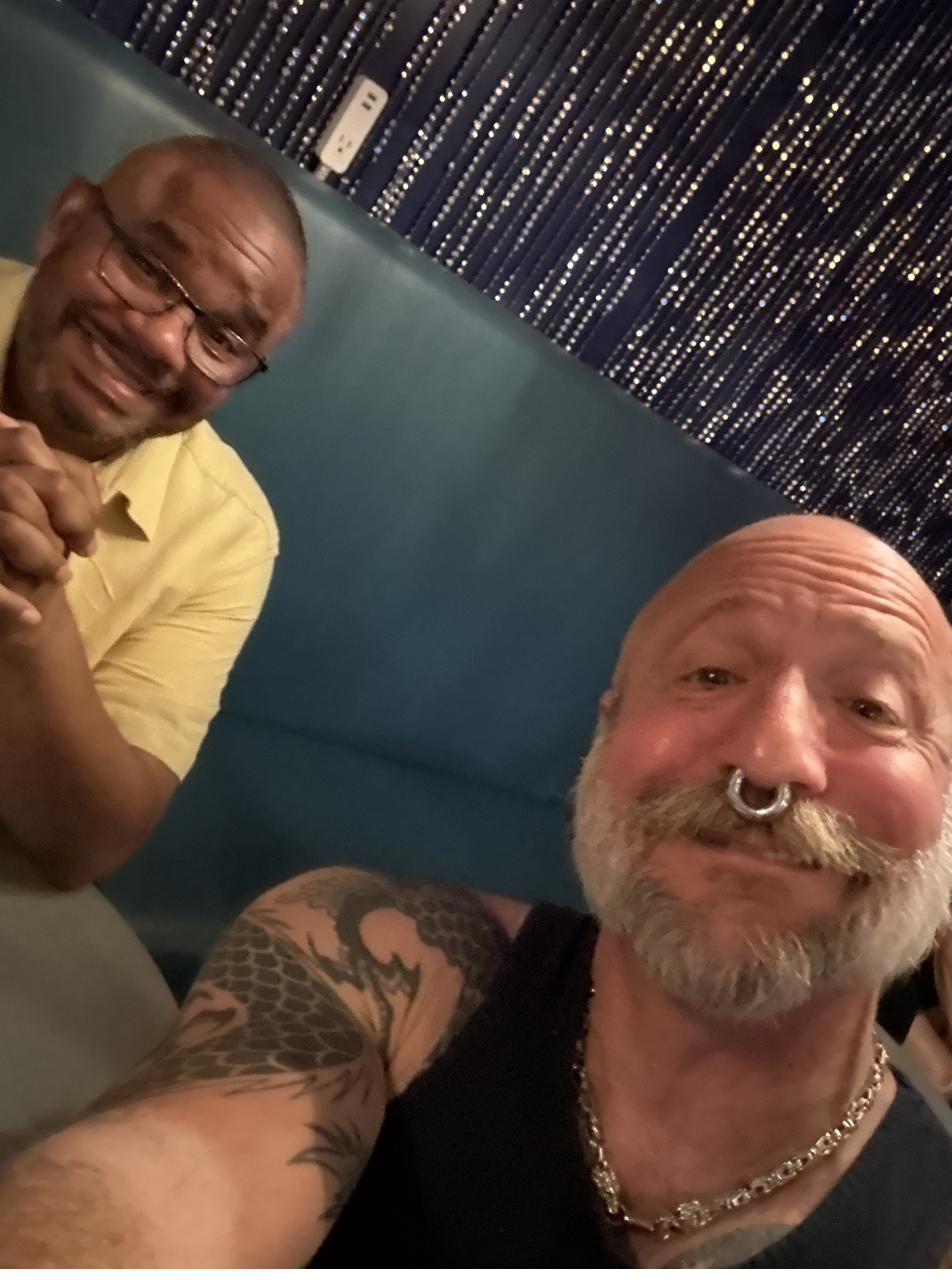 Barclay Barrios and a friend sitting in a restaurant booth.